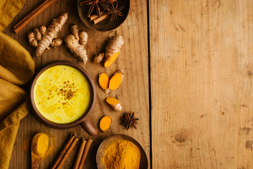 Hot turmeric milk with spices on wooden table