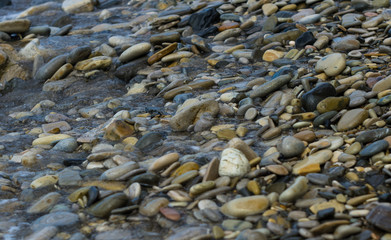 pebble stones on the sea beach, the rolling waves of the sea with foam