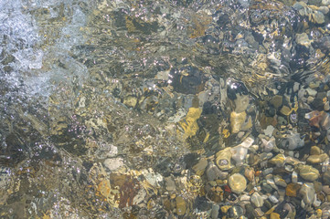 sea pebble beach with multicoloured stones, waves with foam