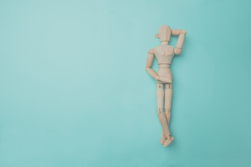 Wooden puppet points aside with its hand. Conceptual image about relax time. Minimal style.