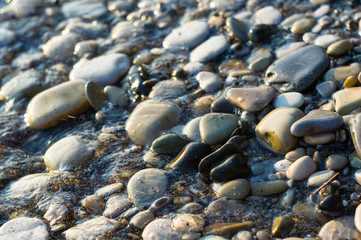 pebble stones on the sea beach, the rolling waves of the sea with foam