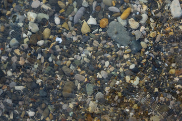 pebble stones on the sea beach, the rolling waves of the sea with foam