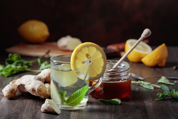 Ginger tea with honey , lemon and mint on old wooden table .