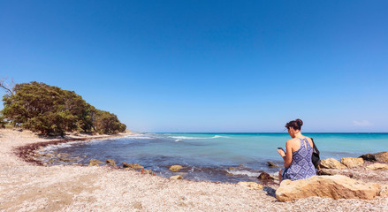 Middle-aged woman with  mobile phone on the Mediterranean coast.