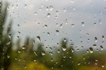 raindrops on window glass on background of cloudy sky