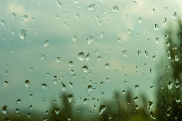raindrops on window glass on background of cloudy sky