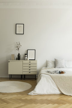 Monochromatic, white bedroom interior with a bed and a nightstand. Breakfast served on the bed. Real photo.