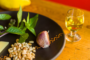 Fresh ingredients for preparing Italian pesto sauce - lemon basil sprigs, peeled seeds of cedar nuts, large garlic clove, Greek olive oil, Parmesan cheese