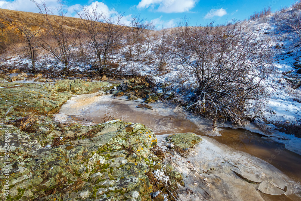 Wall mural Winter frozen creek and stoney bank. Beautiful sunny landscape. Russia, Rostov-on-Don region