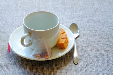 Teacup. Cane sugar, fruit tea in a bag.