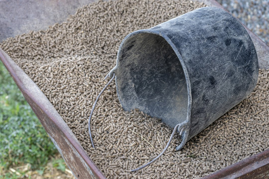 Wheelbarrow with pressed feed chunks and a black bucket .