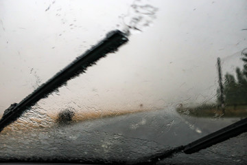 Heavy rain. Cloudburst on windshield. Windscreen wiper and bad visibility.
