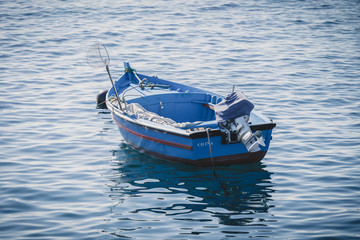 old wooden blue fishing boat on calm water with a fishing net