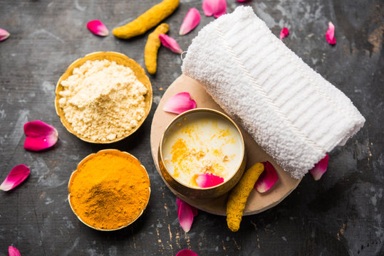 Ayurvedic face pack/mask using Gram Flour/besan, Haldi & milk ubtan placed in brass bowls with rose petals, scrub  and white napkin. selective focus