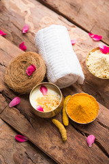 Ayurvedic face pack/mask using Gram Flour/besan, Haldi & milk ubtan placed in brass bowls with rose petals, scrub  and white napkin. selective focus