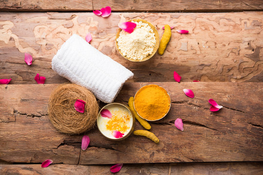 Ayurvedic face pack/mask using Gram Flour/besan, Haldi & milk ubtan placed in brass bowls with rose petals, scrub  and white napkin. selective focus