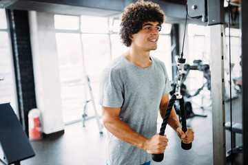 Young handsome man doing exercises in gym