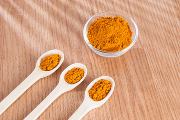 Turmeric powder and fresh turmeric on wooden background.