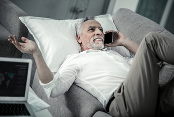 Fototapeta premium Pleasant talk. Happy mature male person having rest while talking per telephone