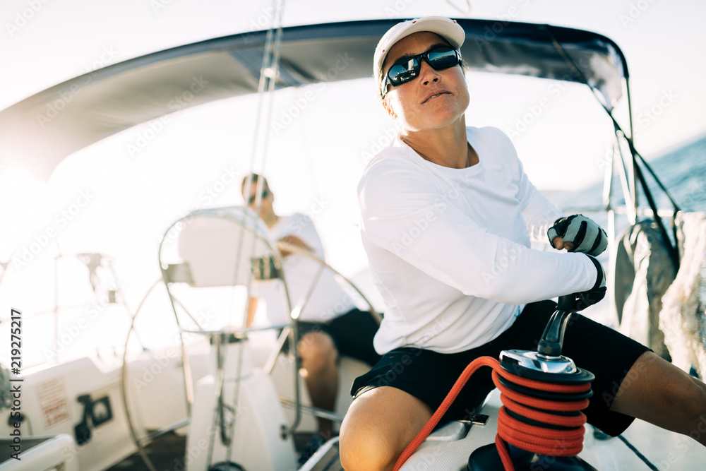 Wall mural Attractive strong woman sailing with her boat