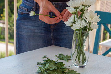 Girl arranging flowers in a glas on a table