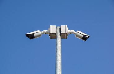 CCTV surveillance security camera on a black pole with blue sky background