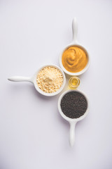 Rai or raw Mustard with sauce, powder and oil, over moody background. Selective focus
