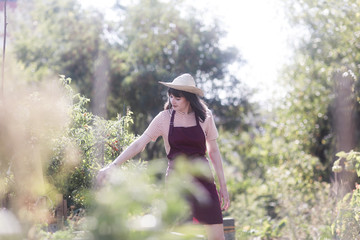 Junge Frau mit Sch&uuml;rze und Strohhut im Garten 