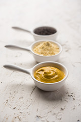 Rai or raw Mustard with sauce, powder and oil, over moody background. Selective focus
