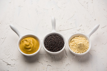 Rai or raw Mustard with sauce, powder and oil, over moody background. Selective focus
