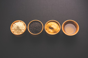 Rai or raw Mustard with sauce, powder and oil, over moody background. Selective focus
