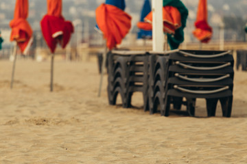 Fototapeta na wymiar Beach umbrellas on foggy morning in Deauville, fashionable holiday resort in Normandy, France. Folded colorful parasols and lounge chairs on the empty beach. Leisure and seaside vacations concept.