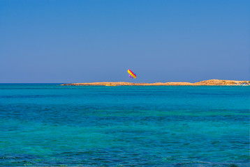 Beautiful turquoise sea, flying small multi-colored parachute in the air – Раrasailing against...
