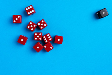 Red and black gaming dices on blue background. Flat lay, game concept.