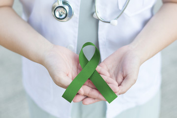 Jade or Emerald green color ribbon awareness in doctor's hand for Liver Cancer and Hepatitis B disease, healthcare medical concept