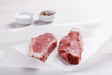 Raw beef striploin steak. Two strip loin steaks on white table.