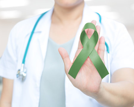Jade green or Emerald color ribbon awareness in doctor's hand for Liver Cancer and Hepatitis B disease, healthcare medical concept
