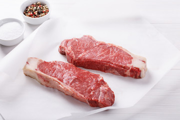 Raw beef striploin steak. Two strip loin steaks on white table.