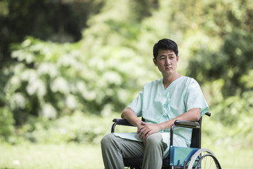 Obraz premium Alone young disabled man in wheelchair at the garden