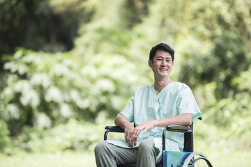 Obraz premium Alone young disabled man in wheelchair at the garden