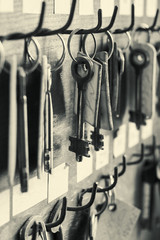 Many old metal keys hanging on the wooden wall with empty labels