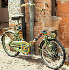 Colored little bicycle tied with a padlock to a pipe at the side of a road
