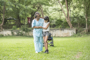 Elderly grandmother in wheelchair with granddaughter in the hospital garden
