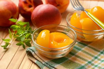 peaches in syrup in the glass bowl with fruit around