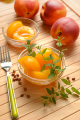 peaches in syrup in the glass bowl with fruit around