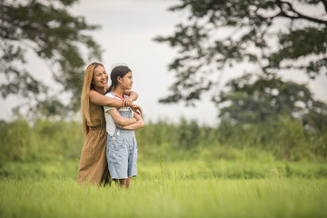 Fototapeta premium Mother and daughter standing happy in grass field