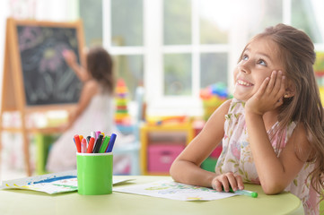 Portrait of cute schoolgirl sitting at table