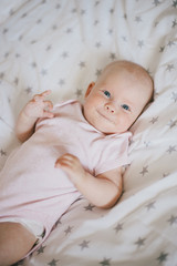 Little cute baby girl wearing pink suit smiling on a bed 