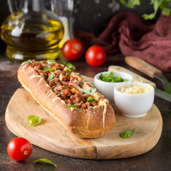 Baguette stuffed with bolognese ragout of minced beef, tomatoes and cheese. A delicious Italian lunch, tasty snacks, homemade sandwich