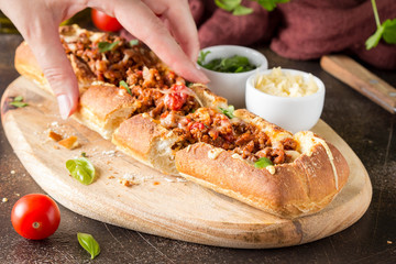 Baguette stuffed with bolognese ragout of minced beef, tomatoes and cheese. A delicious Italian lunch, tasty snacks, homemade sandwich